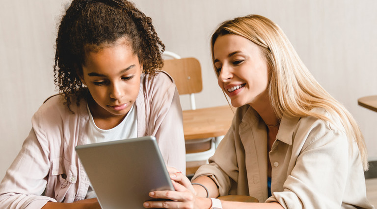 Teacher working with student on tablet in classroom with wi-fi
