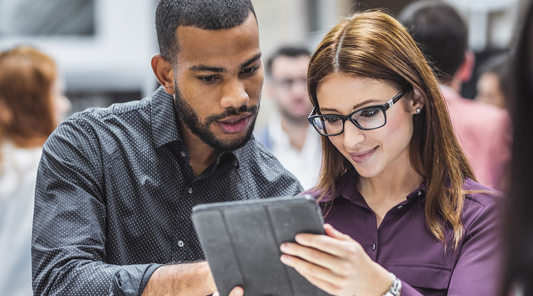 Technology leaders examine tablet in event hall