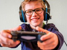 boy with glasses wearing headphones and holding gaming controller