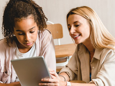 Teacher working with student on tablet in classroom with wi-fi