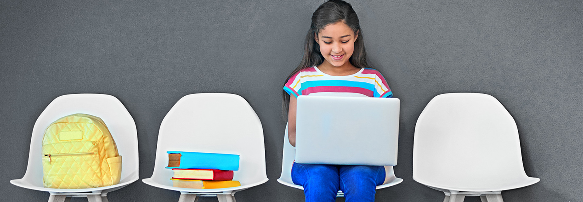 girl in row of chairs on laptop