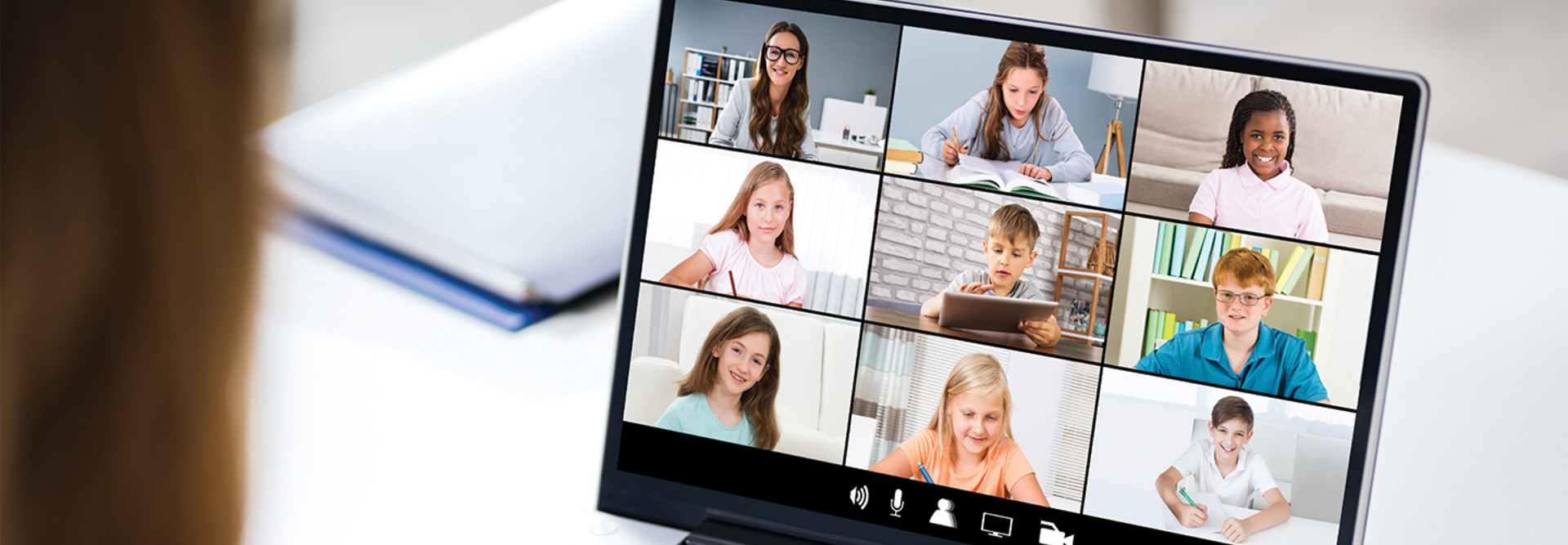 Teacher using laptop at desk video call with students