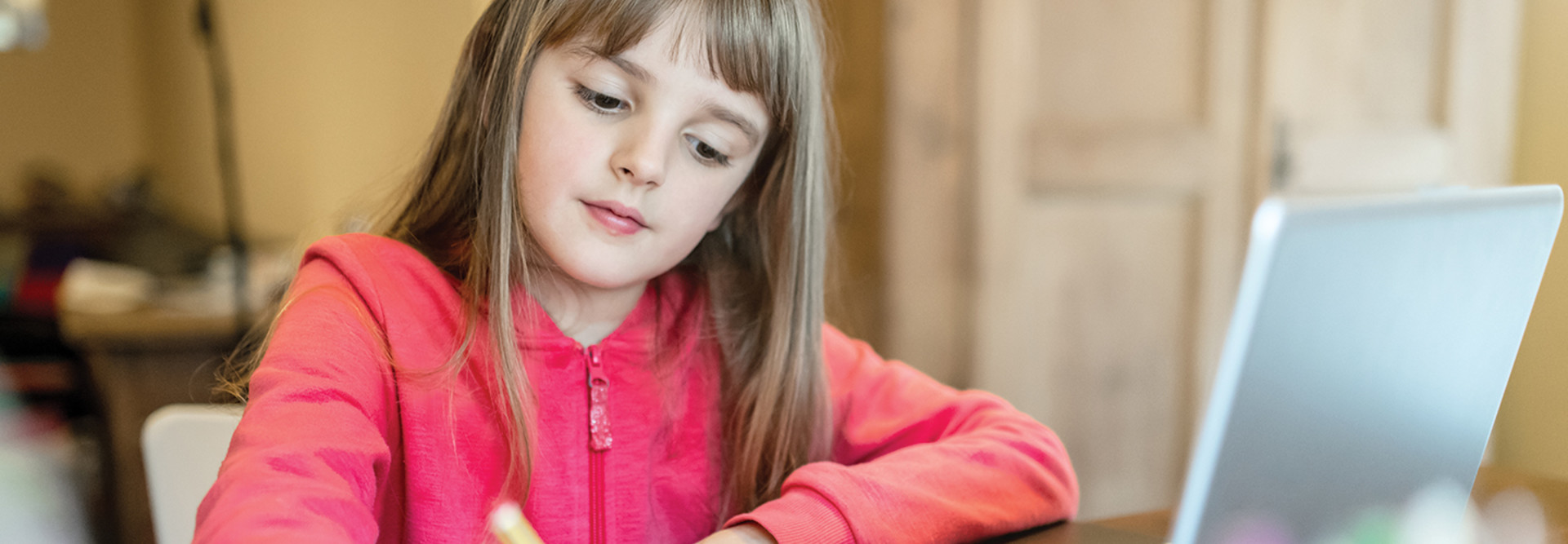 girl taking notes on paper from laptop for school