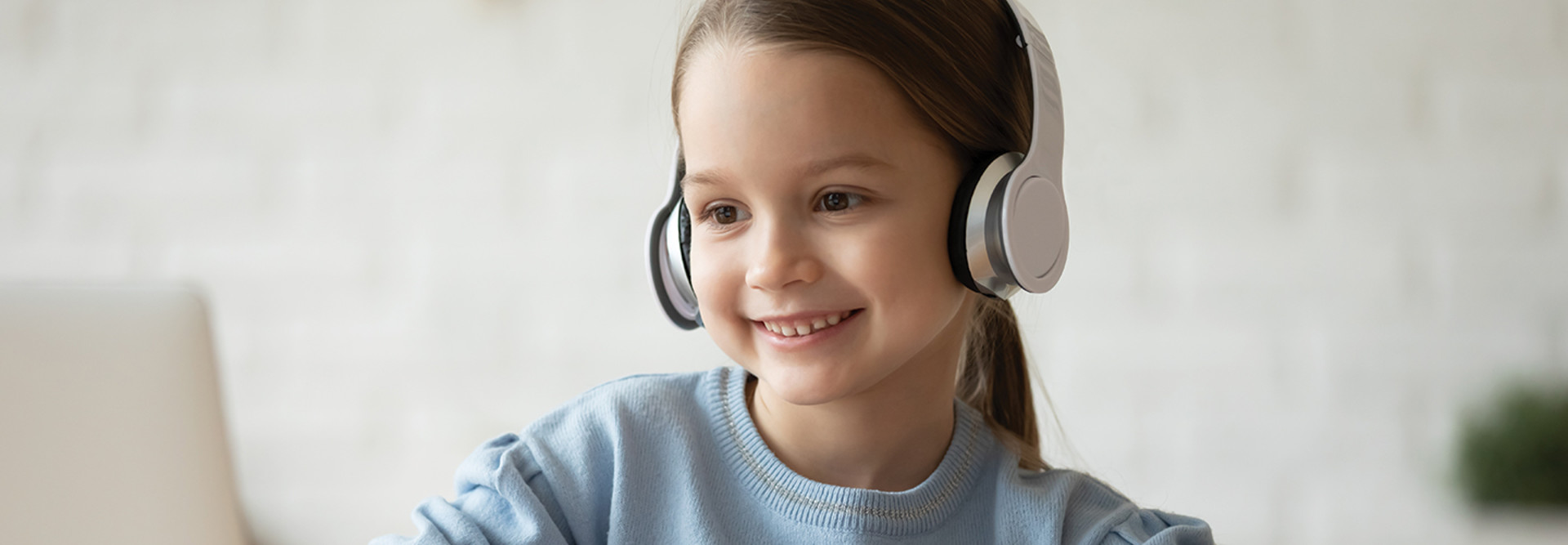 girl with headphones smiling at laptop screen