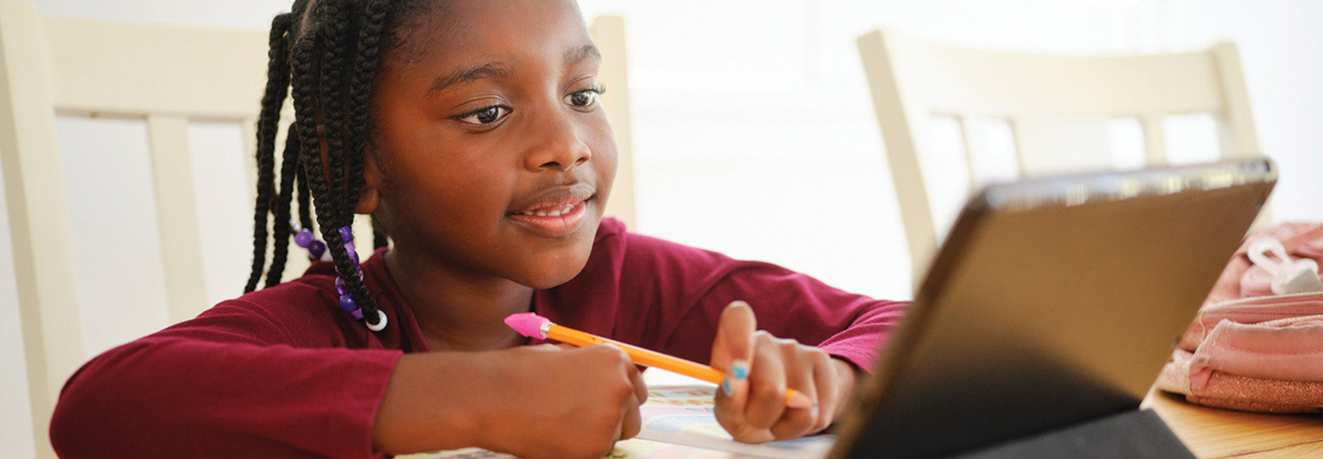 Young girl taking notes on paper while reading tablet 