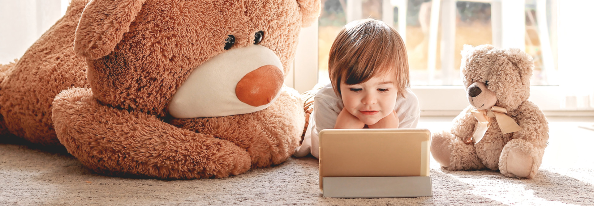 Kindergarten student learns to read on gold tablet with two toy bears