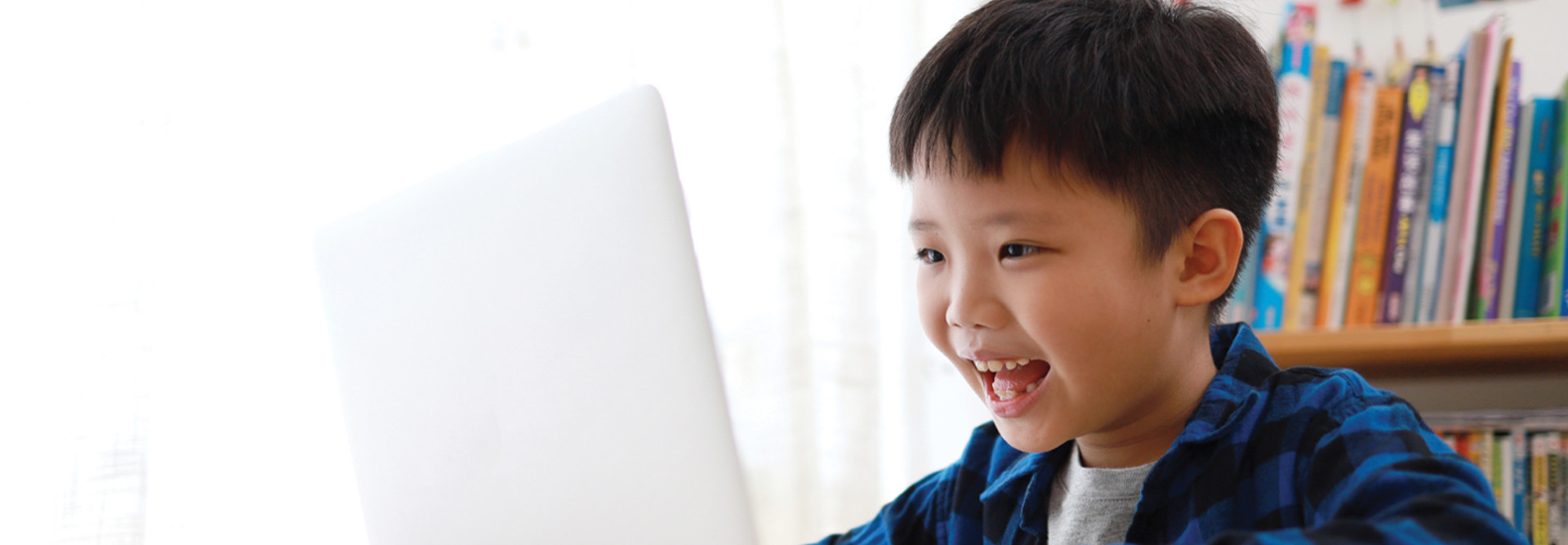 young boy online learning smiling at his computer