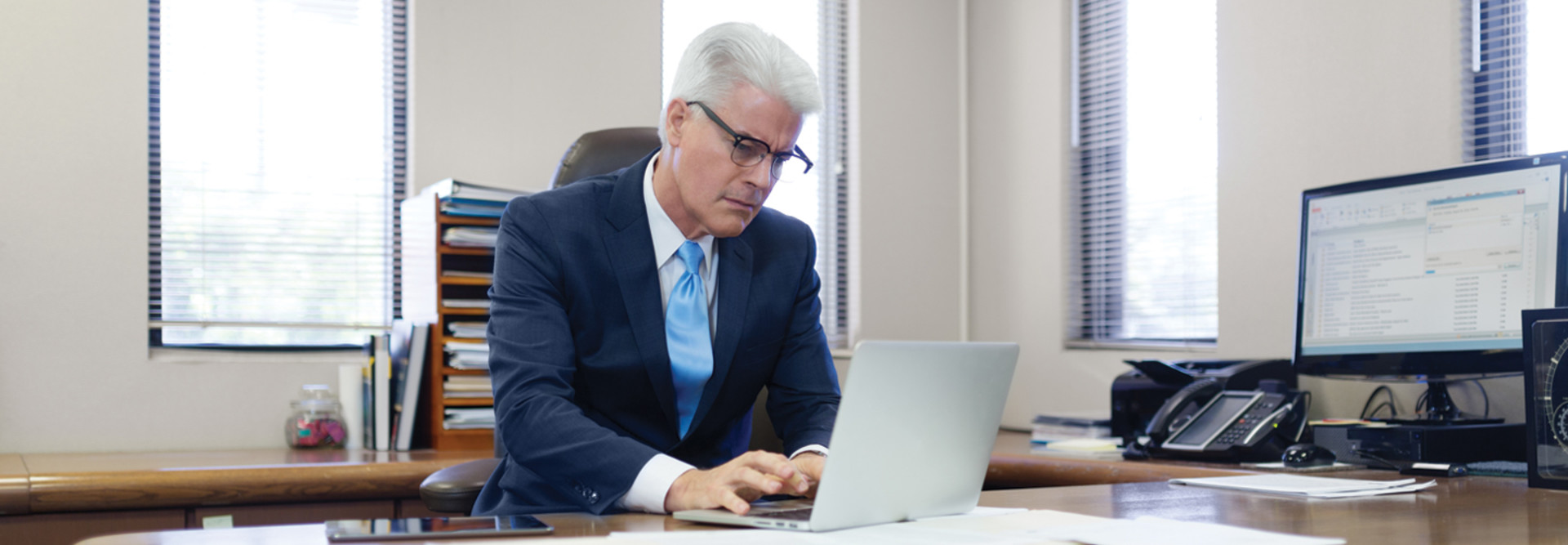 Administrator at desk looking at paperwork and laptop federal funding 