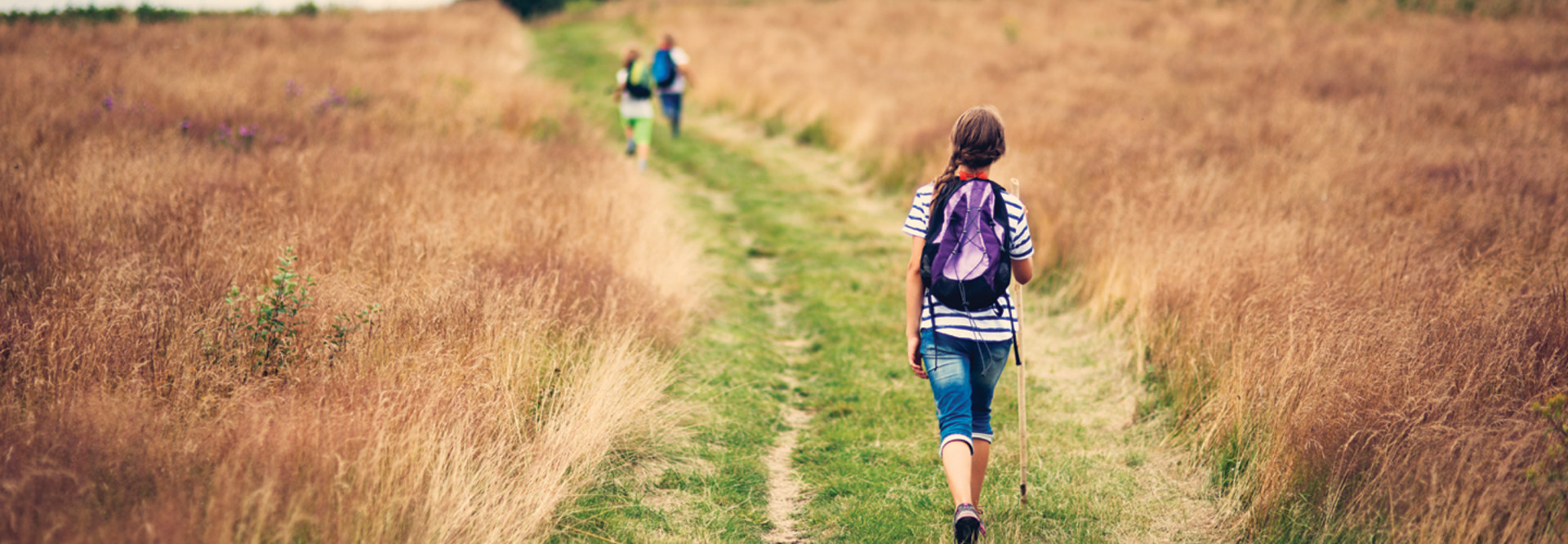 Rural k-12 students on grass road with backpacks