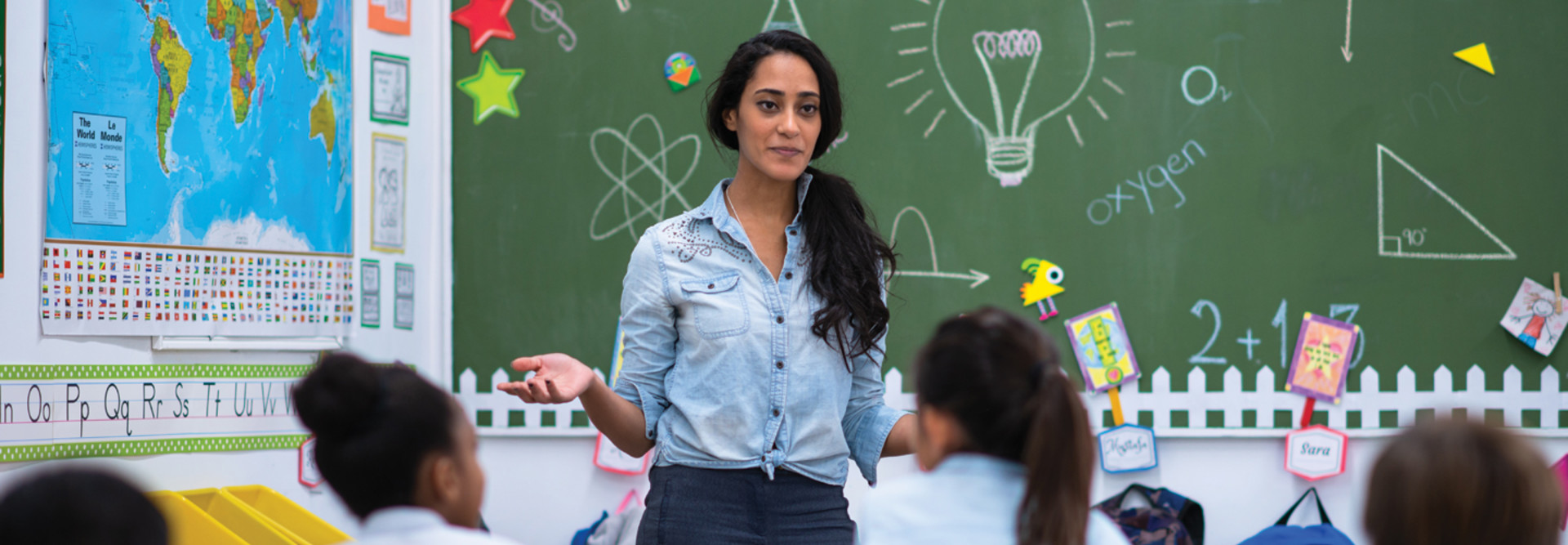 K-12 teacher asking question in classroom of students 