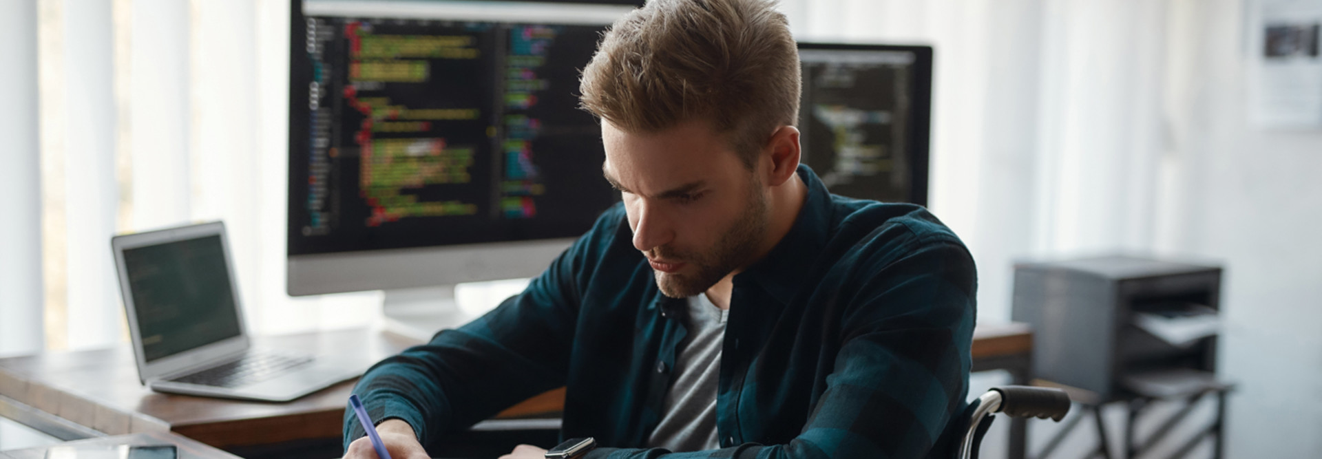 Man working with data on desktop and laptop computers