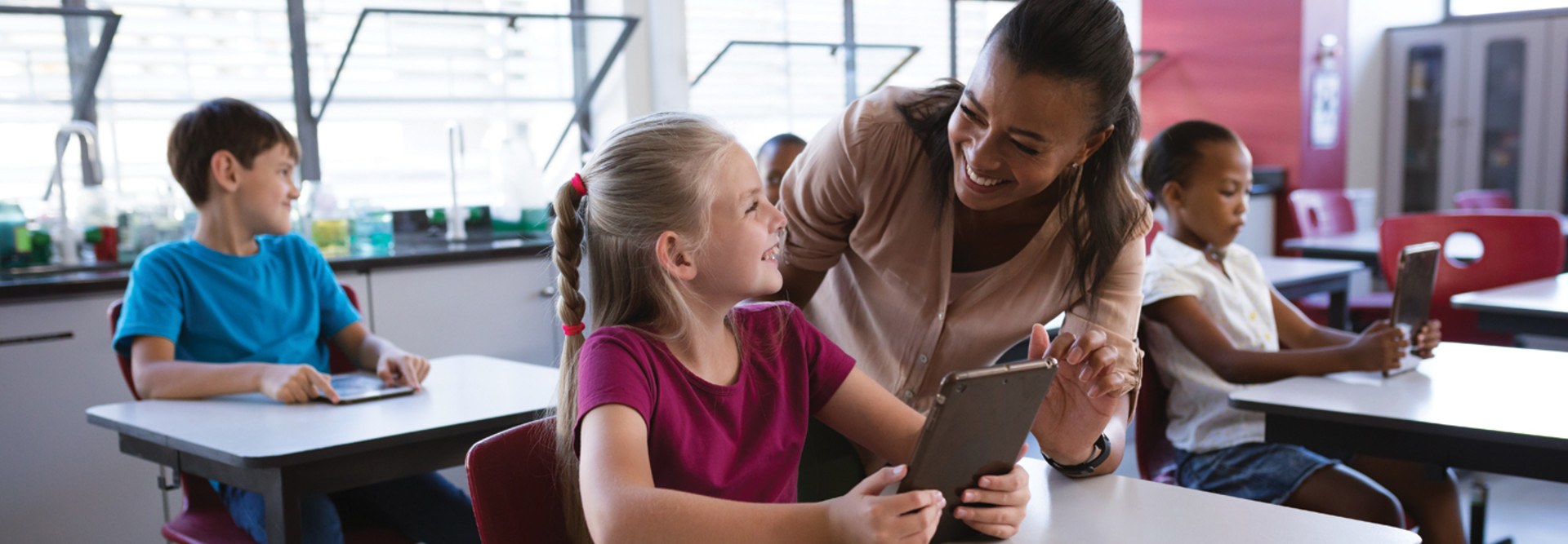 K-12 classroom teacher helping student with tablet