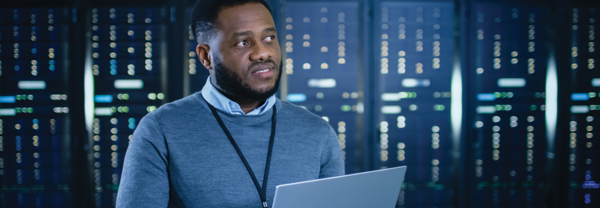 IT professional standing in data center with laptop
