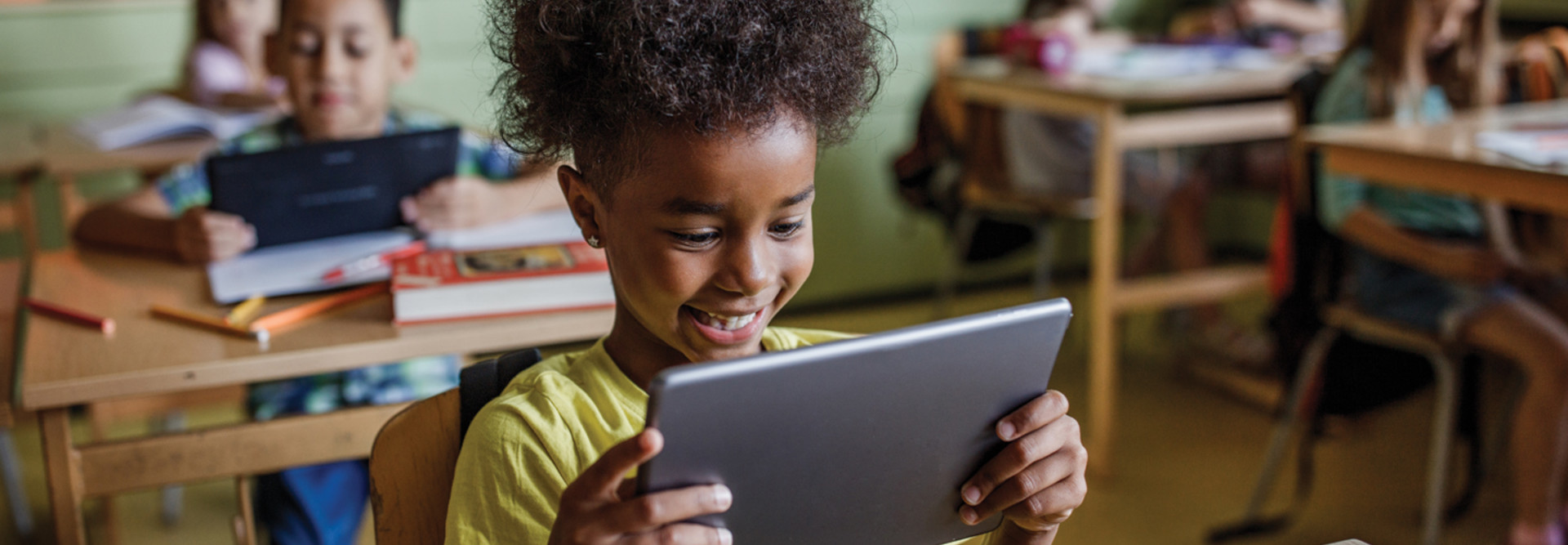 K-12 student using mobile tablet device in modern classroom