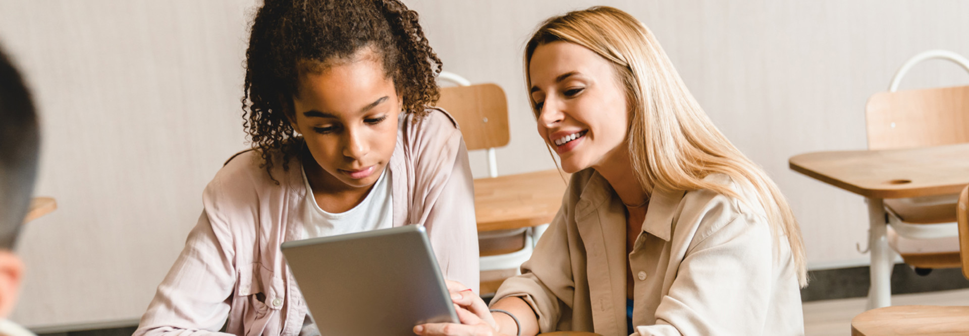 Teacher working with student on tablet in classroom with wi-fi