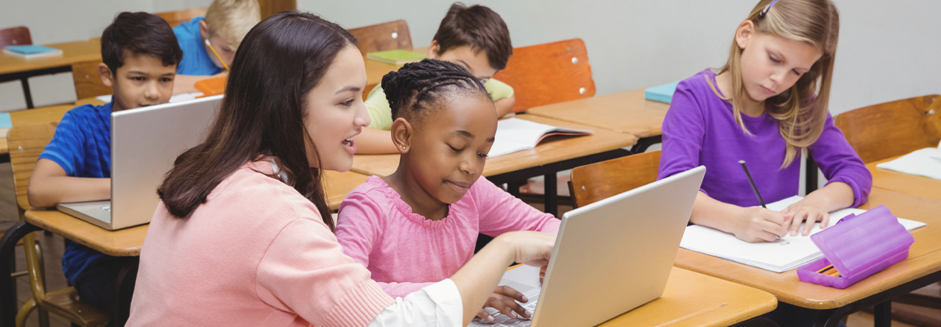 Teacher assisting student with laptop