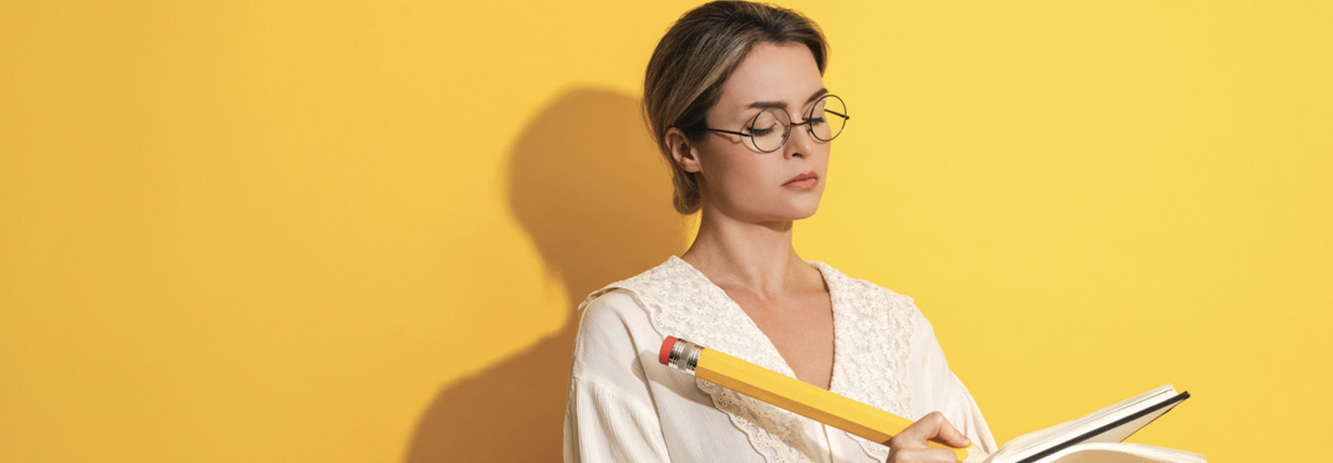 Person using an oversized pencil and notebook