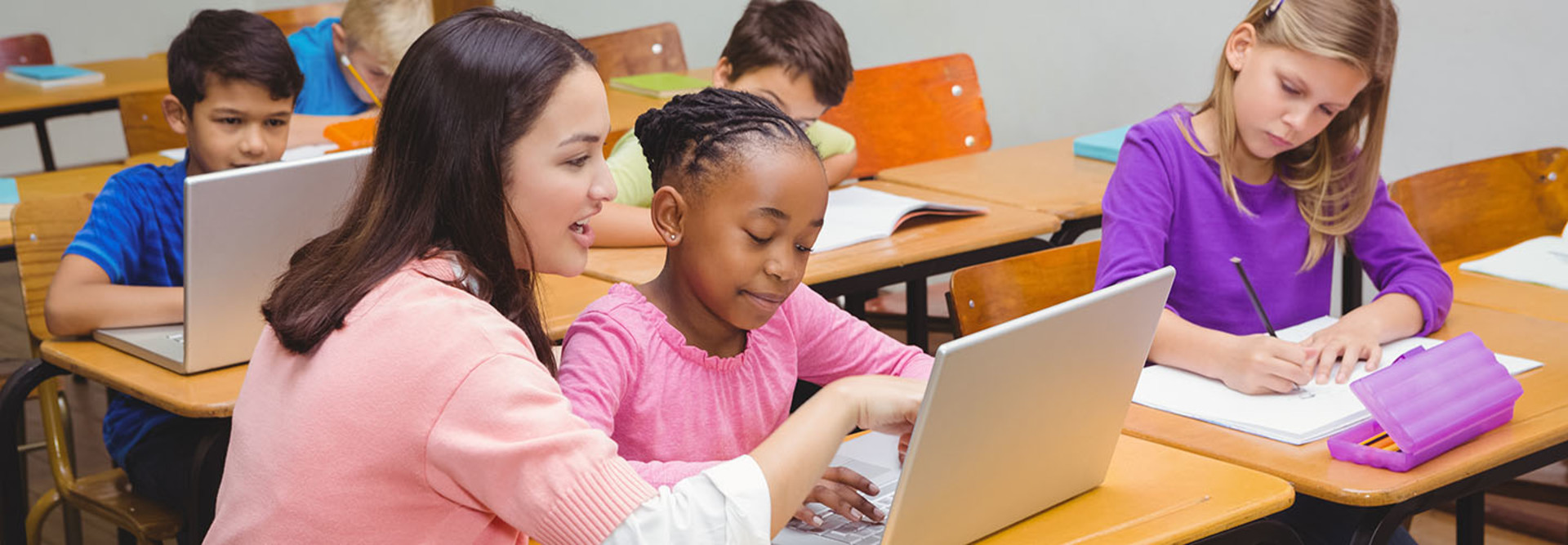 Teacher using laptop with student