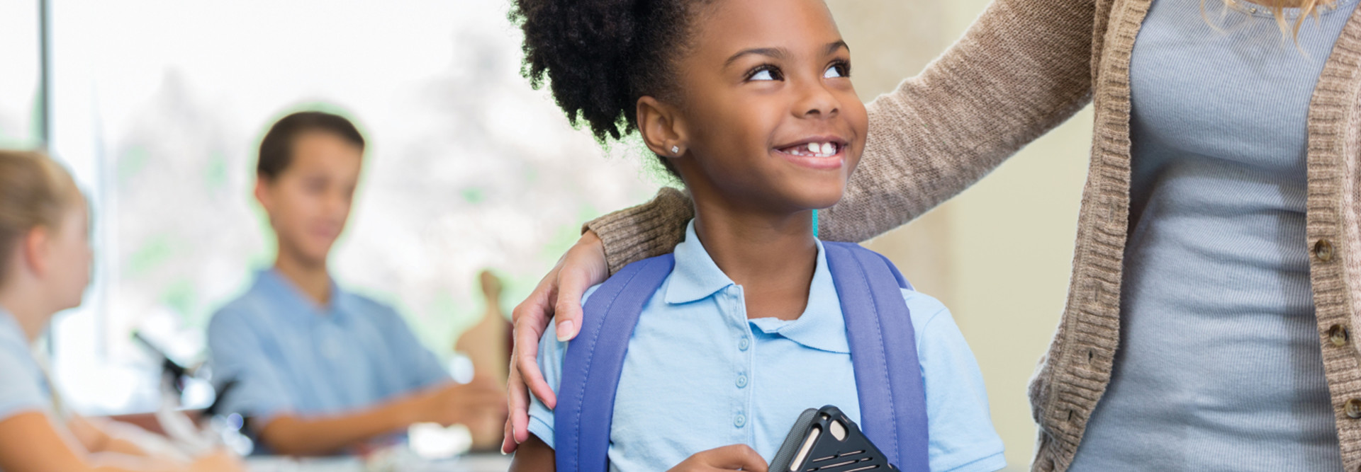 Independent school student with tablet smiling at teacher