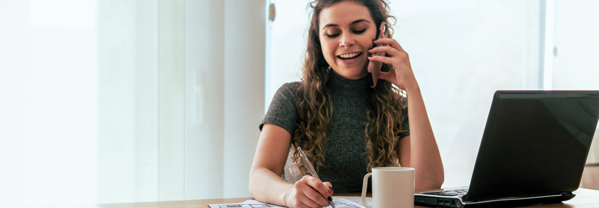 Person speaking on phone using laptop