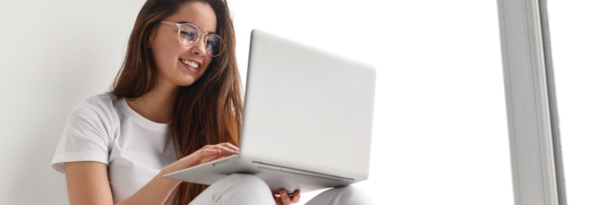 Student using laptop near window