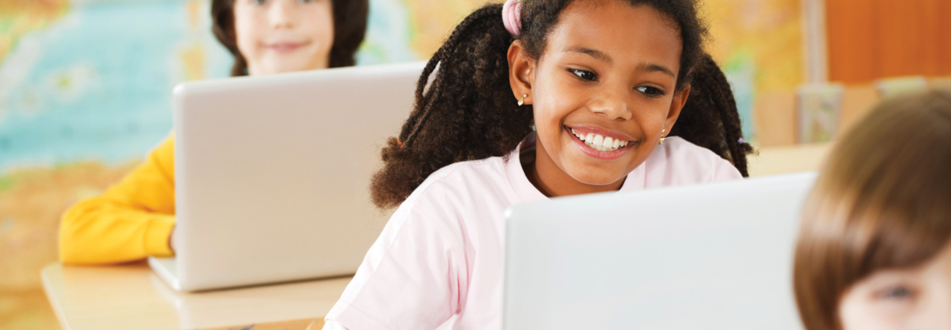 Three pupils sitting in a row and using their laptops