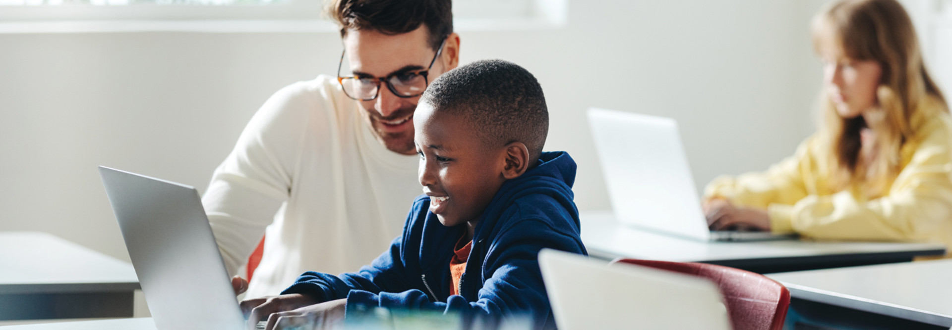 teacher helping students in K12 education working on computers