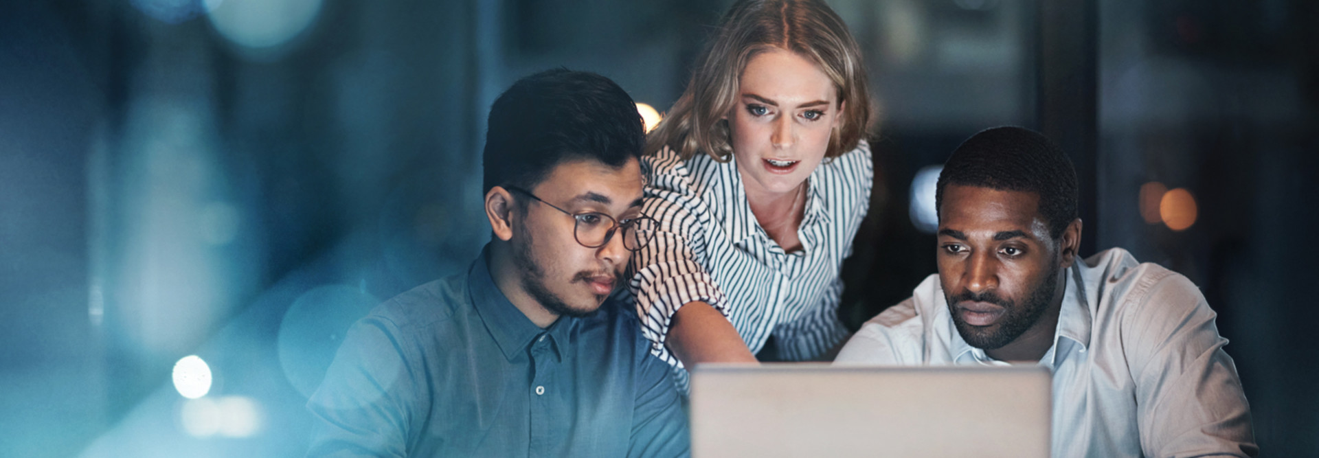 Three people looking at a laptop screen.