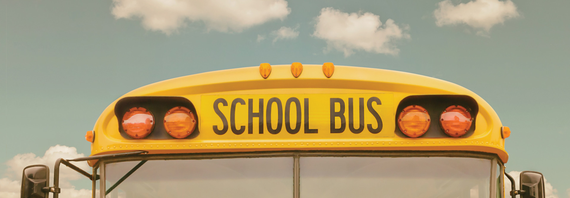 The front of a school bus against a cloudy sky