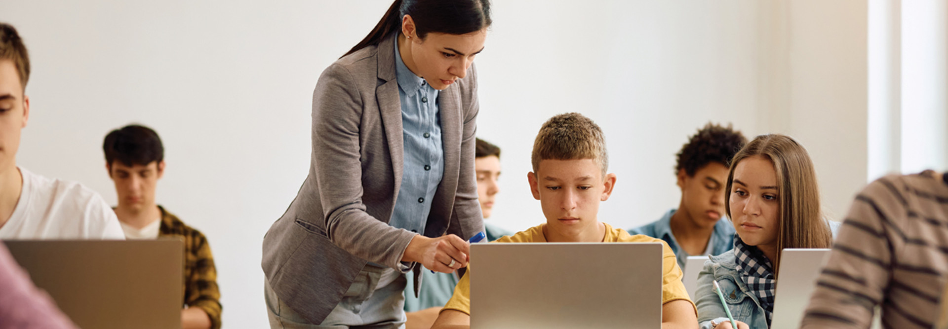 teacher helping students use laptops for school lessons