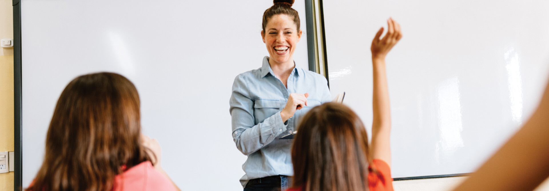 A teacher in the front of a classroom teaching students.