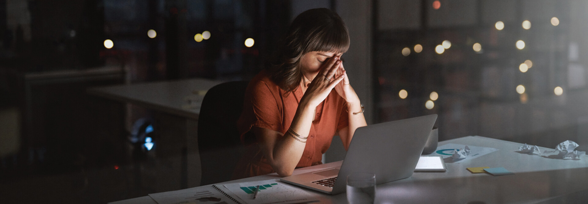 Woman sitting in front of a laptop looking concerned late at night