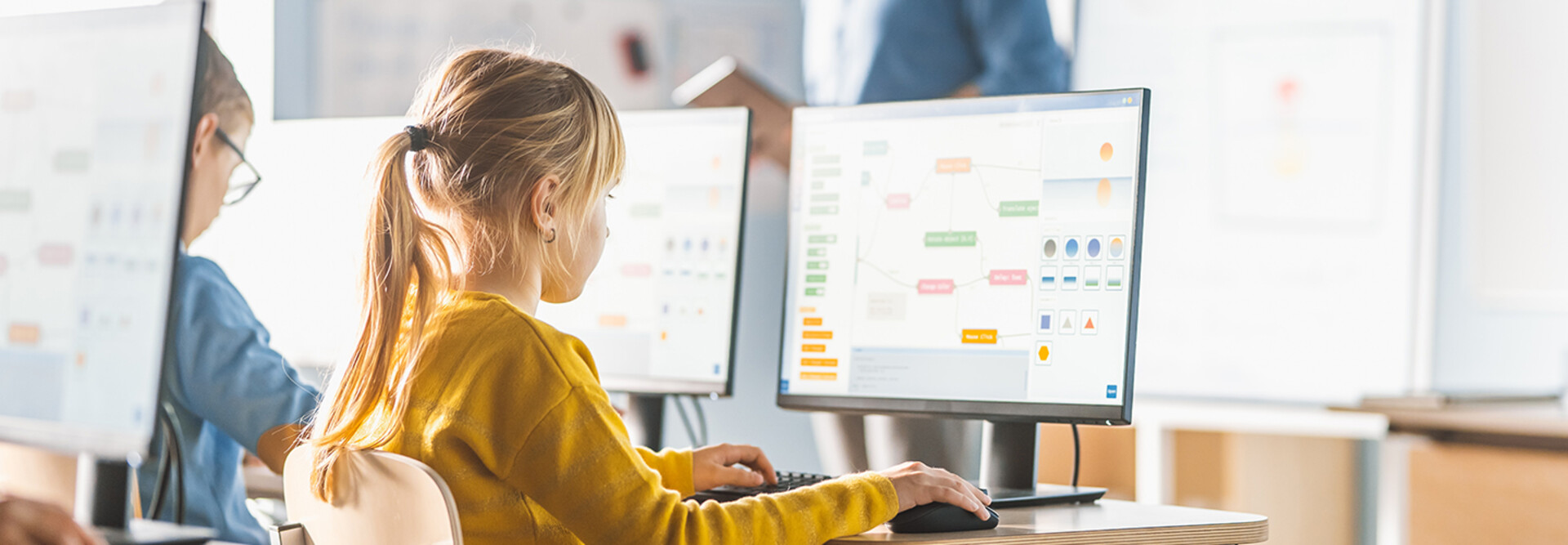 Kids in a classroom viewing the same information on their own monitors.
