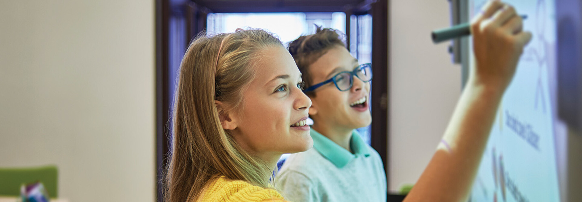students smiling while writing on digital whiteboard