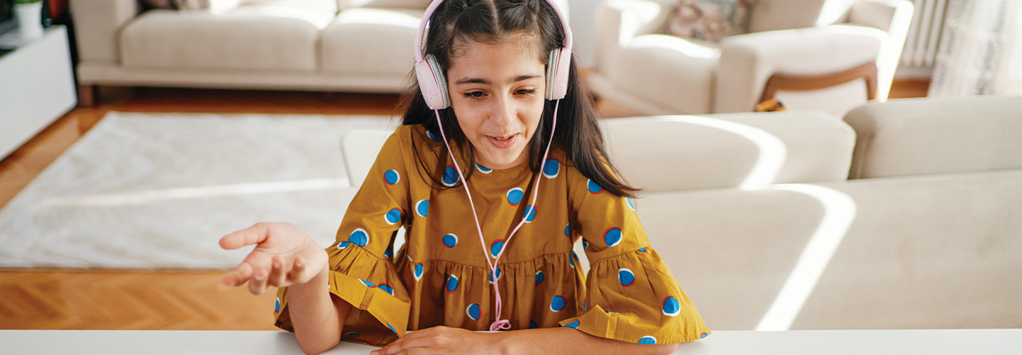 teenage girl with headphones and laptop having online class