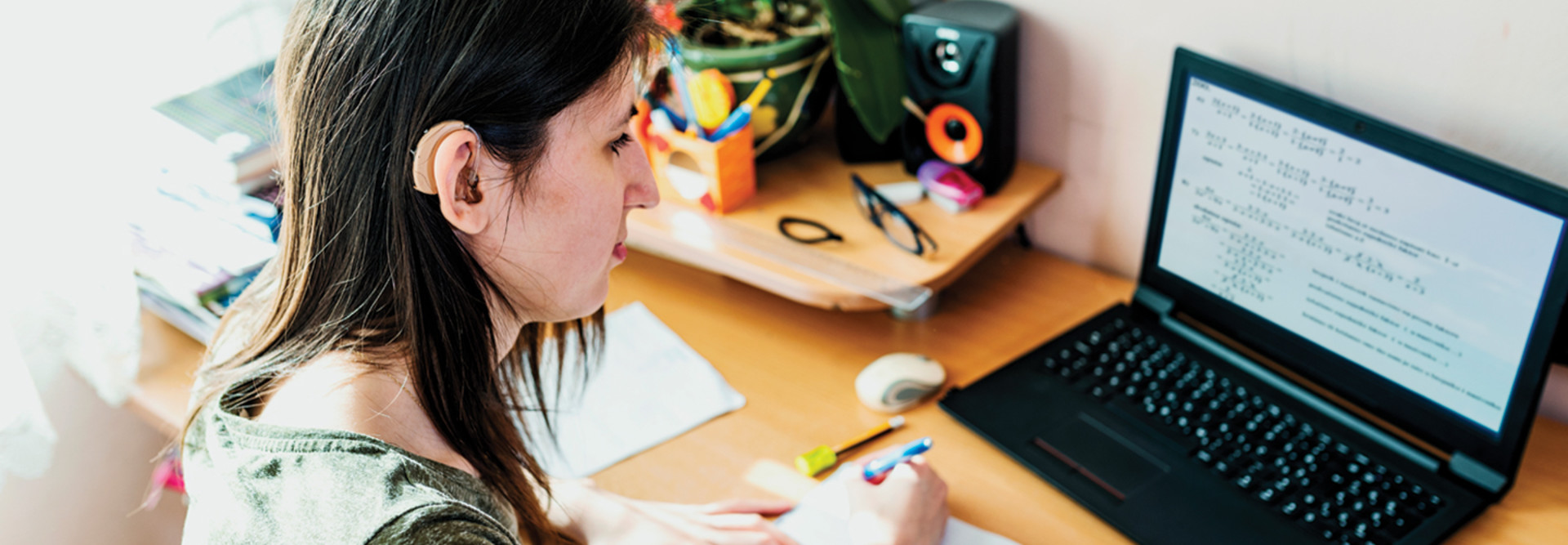 Student with hearing aid studying on computer