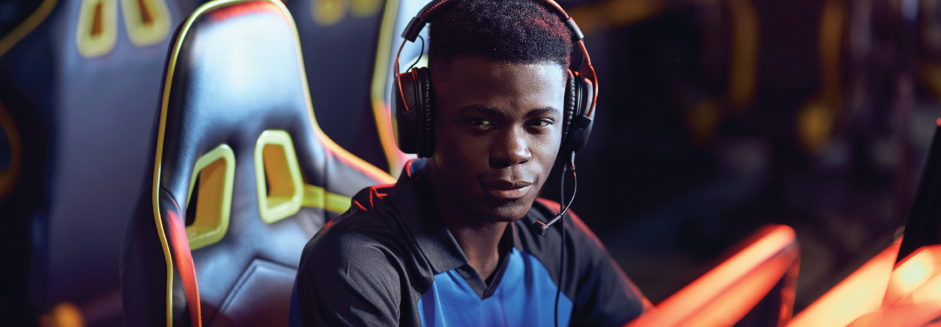 Student wearing headphones sitting in front of desktop computer playing esports