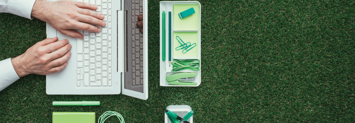 Tech sustainability concept, laptop and office supplies on grass