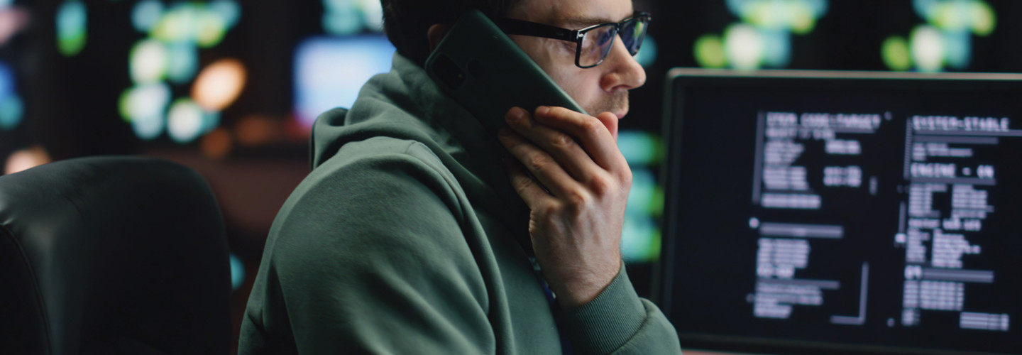 Man talking on cell phone surrounded by computers and data