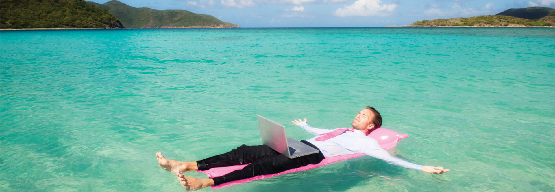 Person floating in the ocean while working on a computer