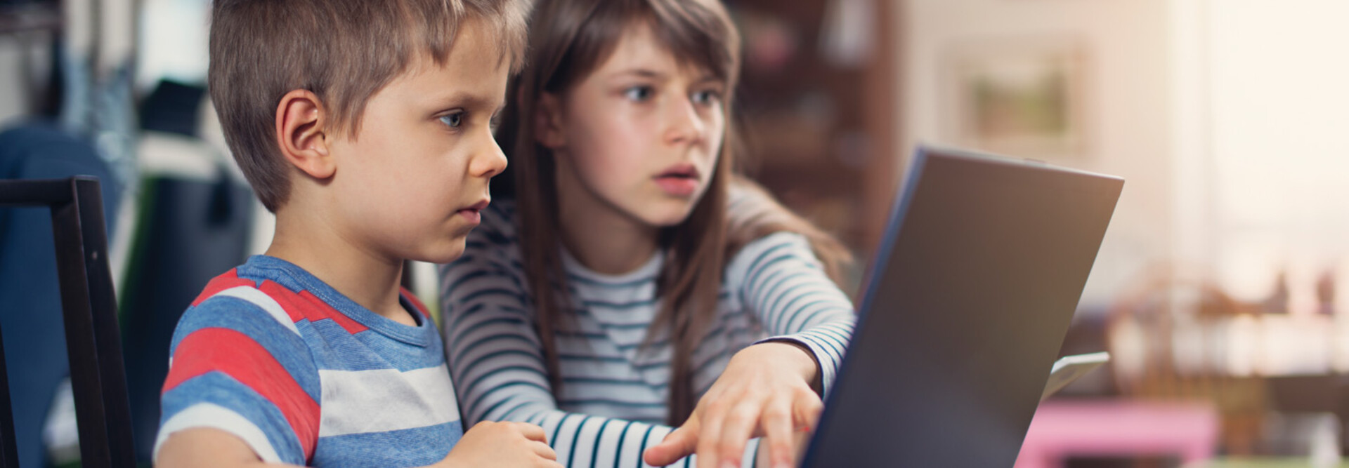 Two K–12 students working on a school laptop together