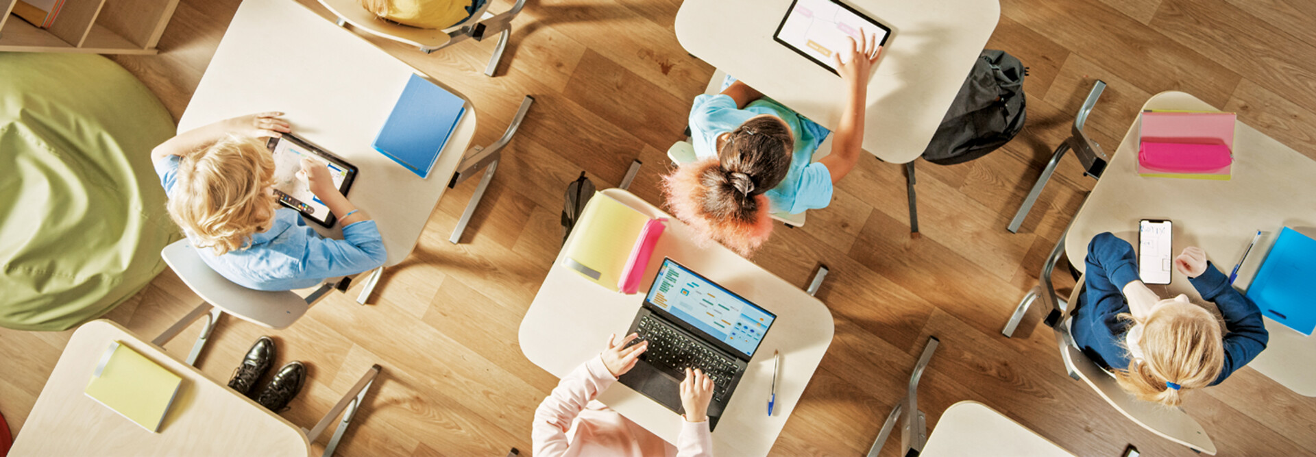 Overhead view of children sitting at desks working in a classroom on computers