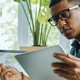 Busy young mixed race man using technologies while working in the office