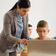 teacher helping students use laptops for school lessons