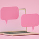 computer against pink backdrop with floating pink speech bubbles to indicate chatroom