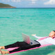 Person floating in the ocean while working on a computer