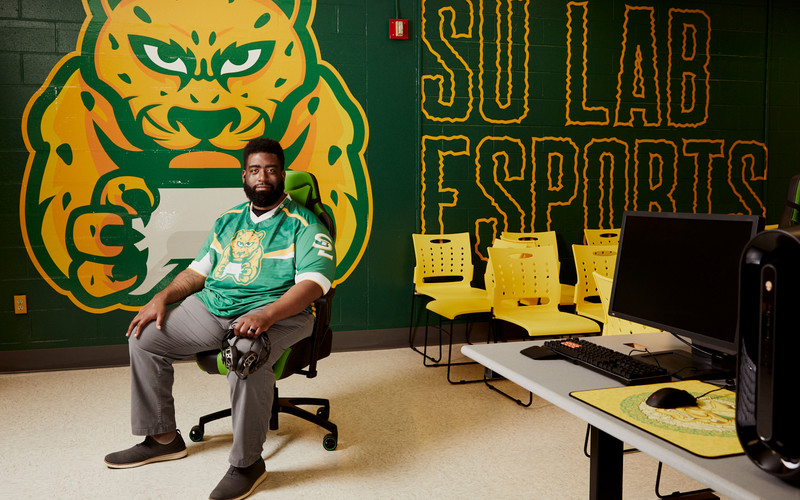 Coach Turner in his esports jersey in front of the esports lab mural