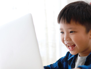 young boy online learning smiling at his computer