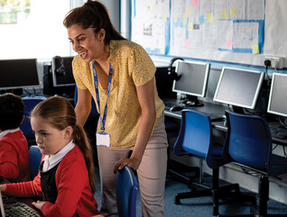 K-12 Teacher preparing a student for online testing on desktop with keyboard