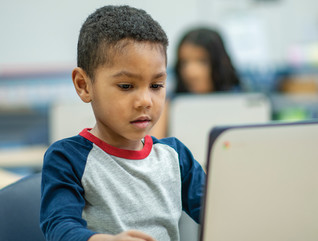 K–12 student using laptop device in classroom for learning
